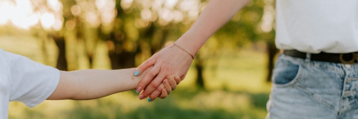 a couple of people holding hands in a field